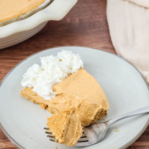 A slice of no-bake pumpkin pie with a bite taken out of it by a fork.