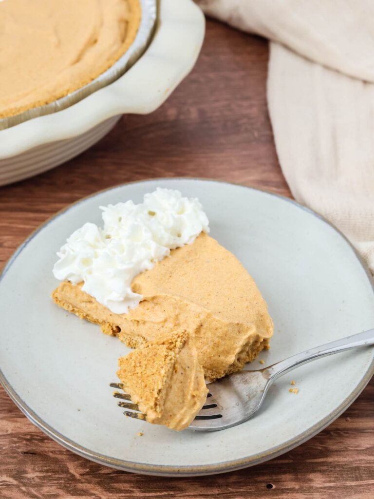 A slice of no-bake pumpkin pie with a bite taken out of it by a fork.