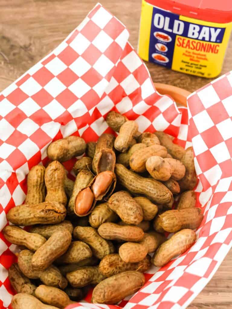 Old Bay boiled peanuts in a basket, with a container of seasoning behind it.
