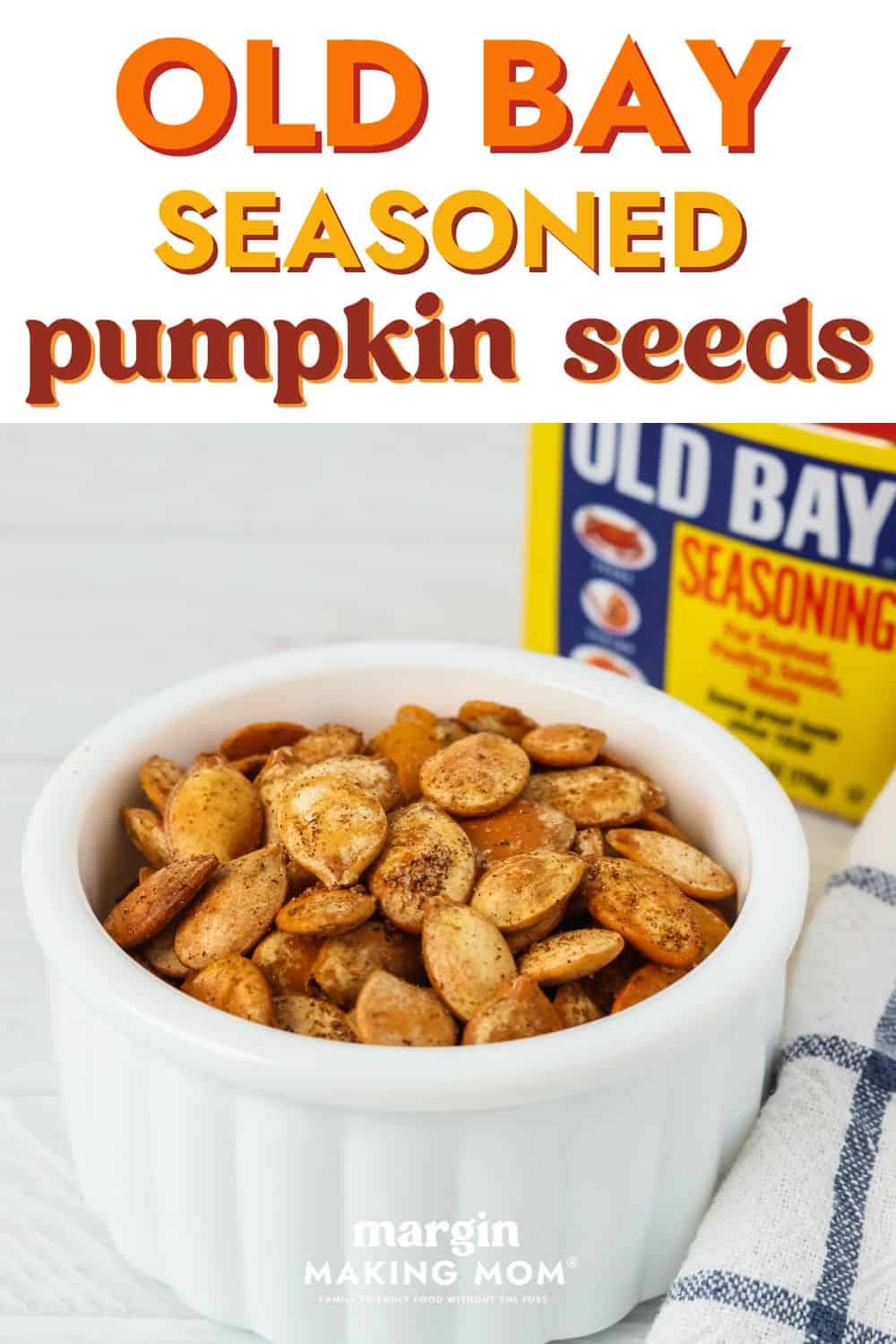a white dish of Old Bay pumpkin seeds, with a container of Old Bay seasoning in the background.