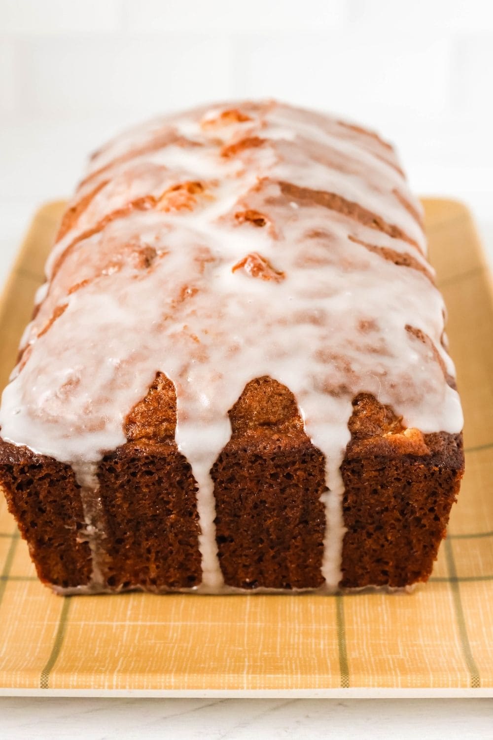close-up end view of a loaf of fresh peach bread topped with white powdered sugar glaze.
