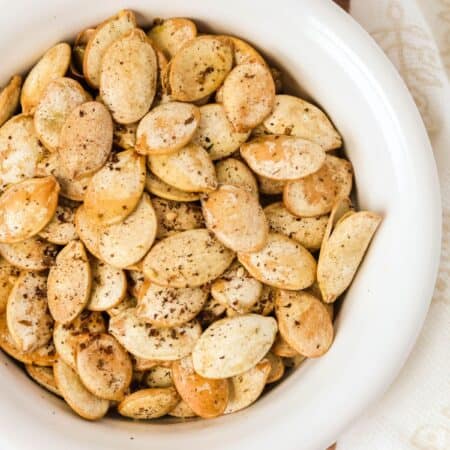 Golden brown Za'atar seasoned pumpkin seeds served in a white bowl.