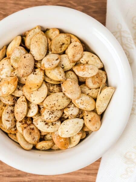 Golden brown Za'atar seasoned pumpkin seeds served in a white bowl.