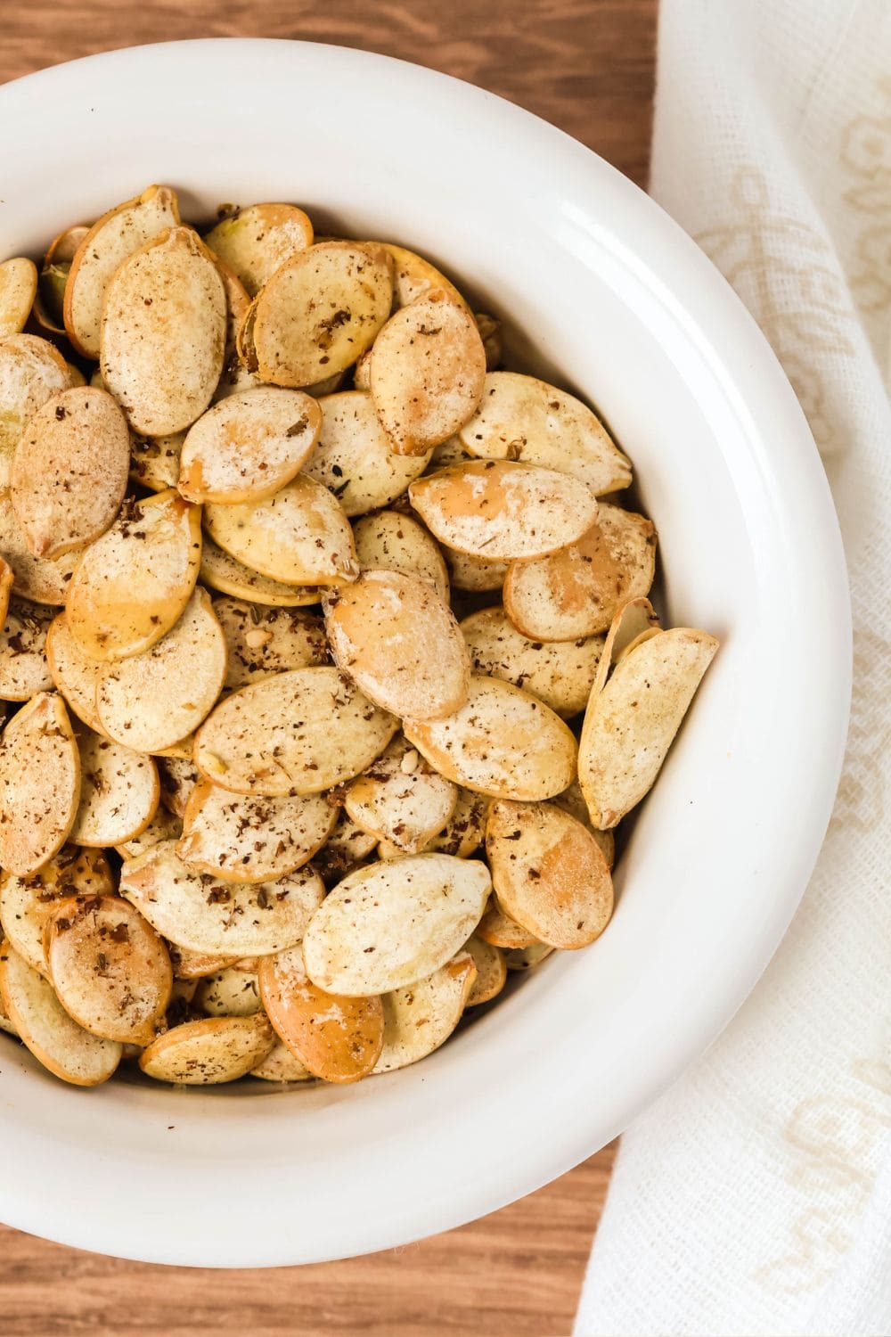 overhead view of za'atar seasoned pumpkin seeds in a white bowl.