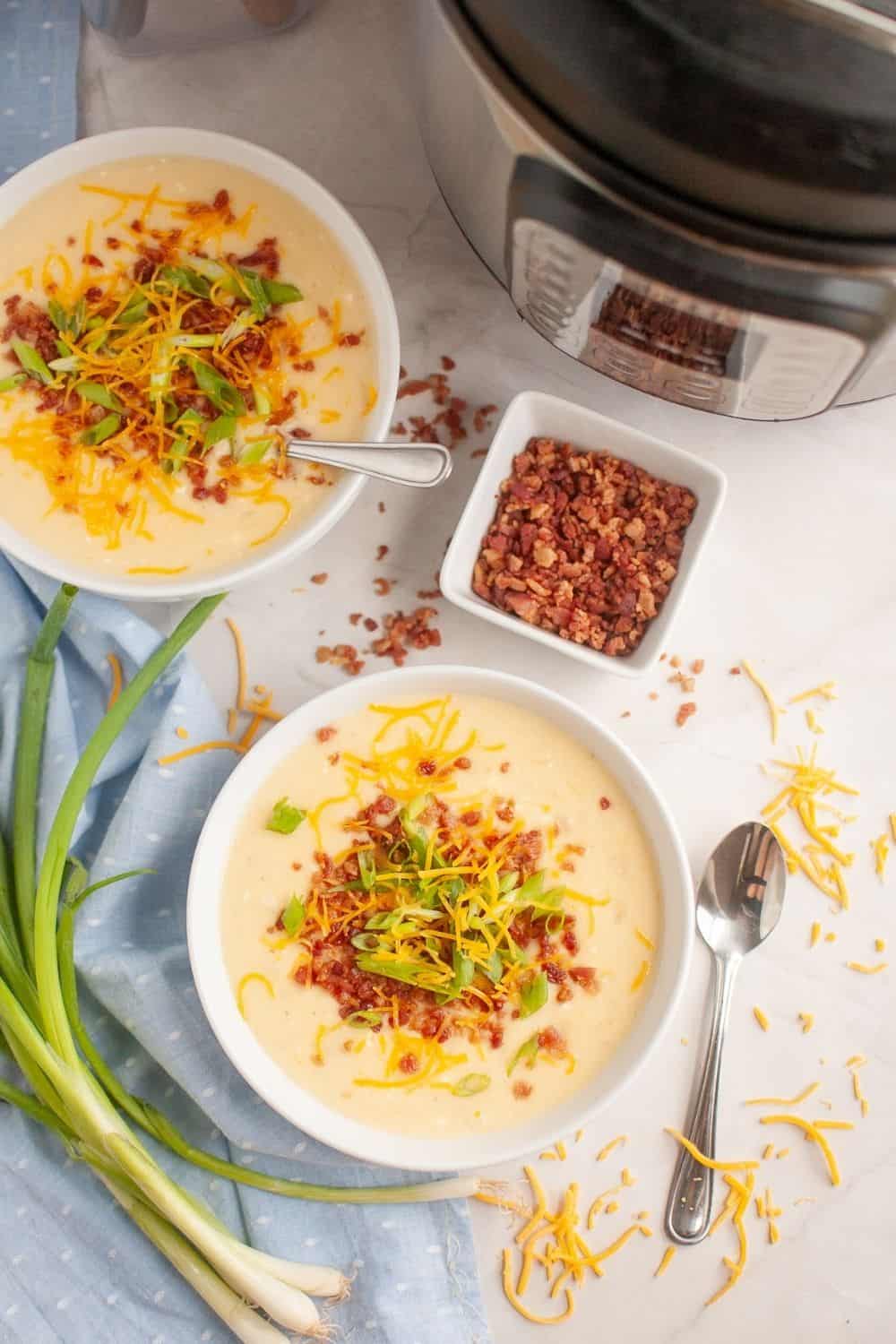 overhead view of two bowls of Instant Pot loaded potato soup, made with frozen hash brown potatoes, next to an Instant Pot pressure cooker.