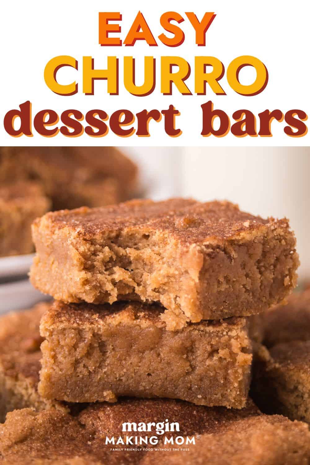 a few homemade churro bars are stacked on top of each other; one has a bite taken out of it.