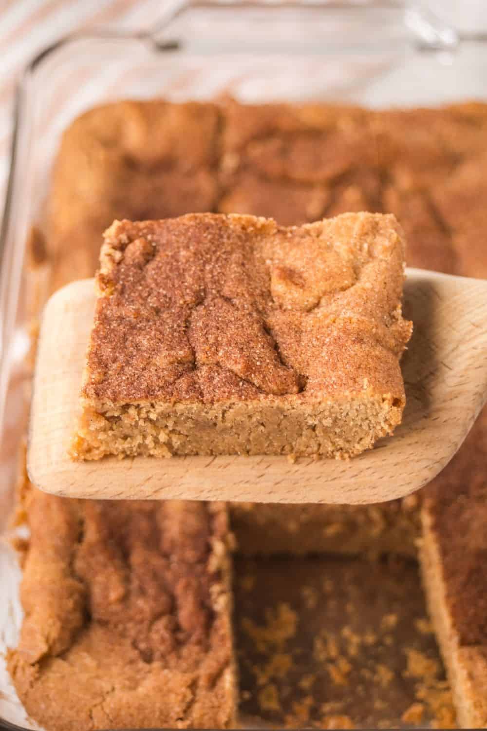 a wooden spatula lifts a churro blondie from the pan.