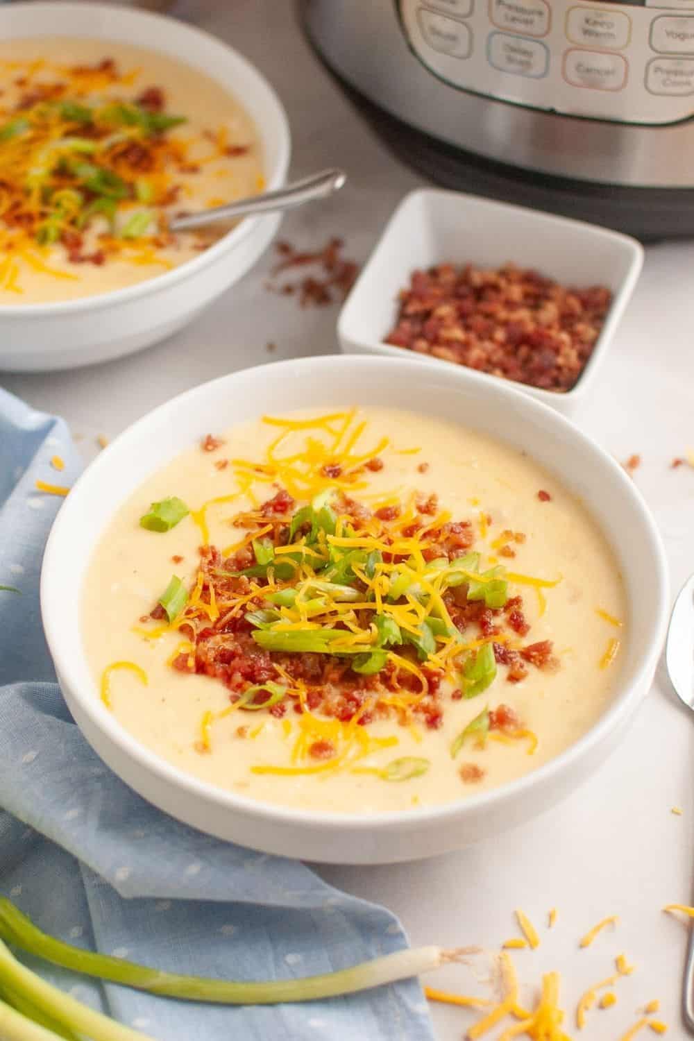 A bowl of potato soup made with frozen hash browns, in front of an Instant Pot pressure cooker.