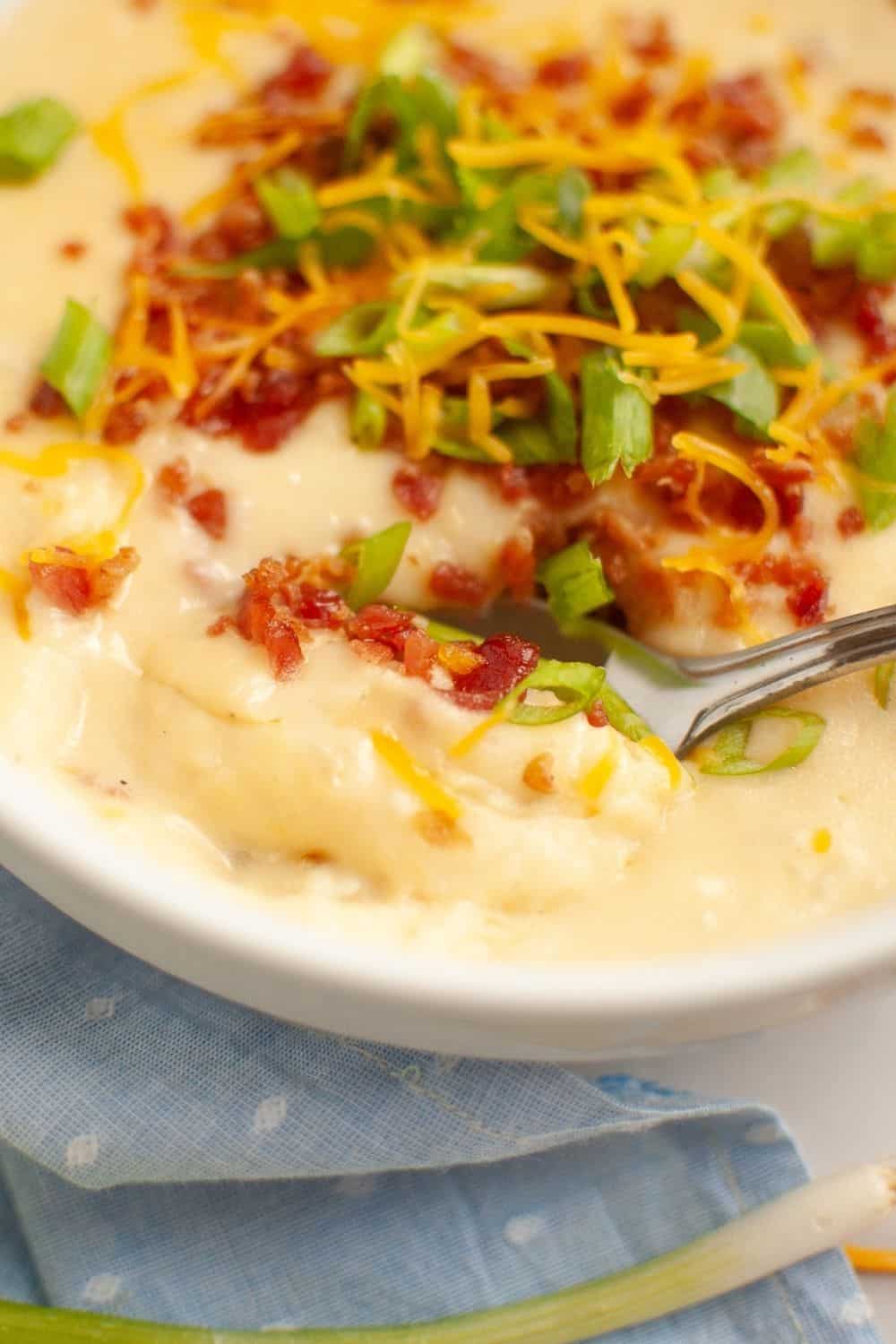 close-up view of a spoon in a bowl of creamy loaded potato soup.
