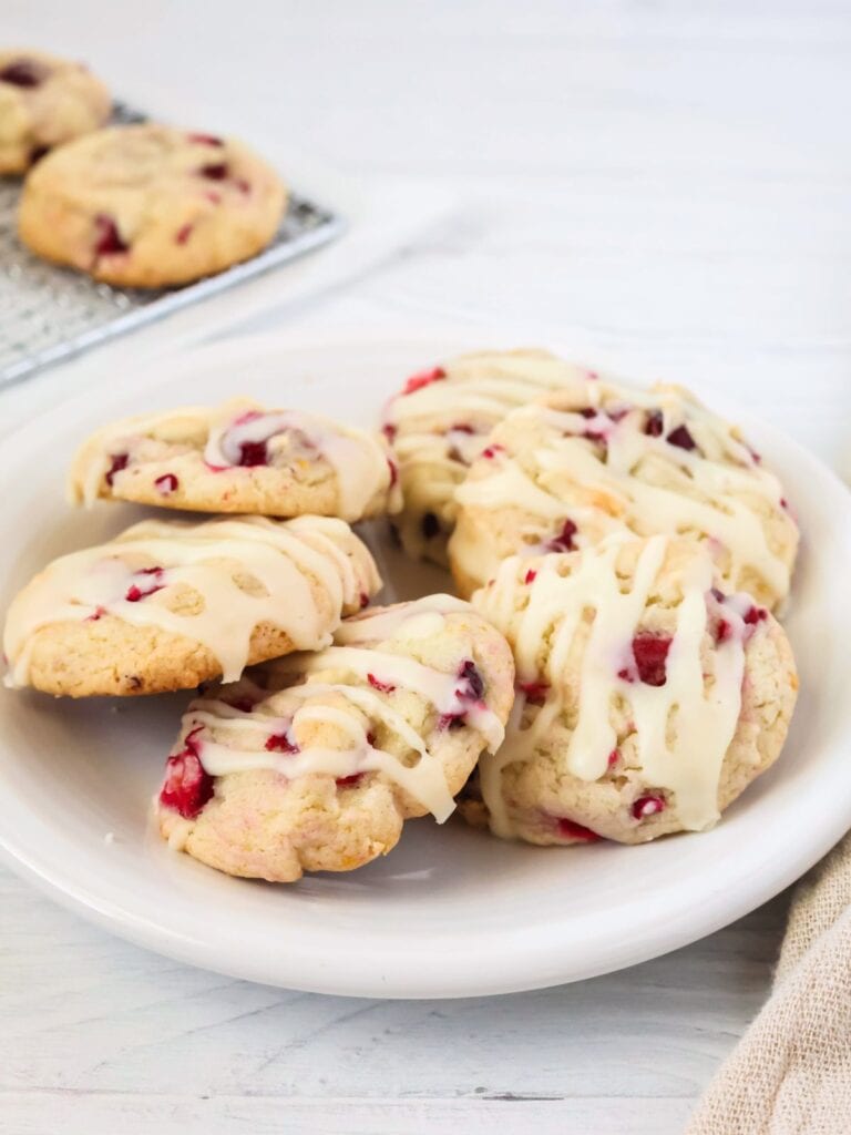 Cake mix cranberry orange cookies served on a white plate. The cookies are topped with a drizzle of icing.