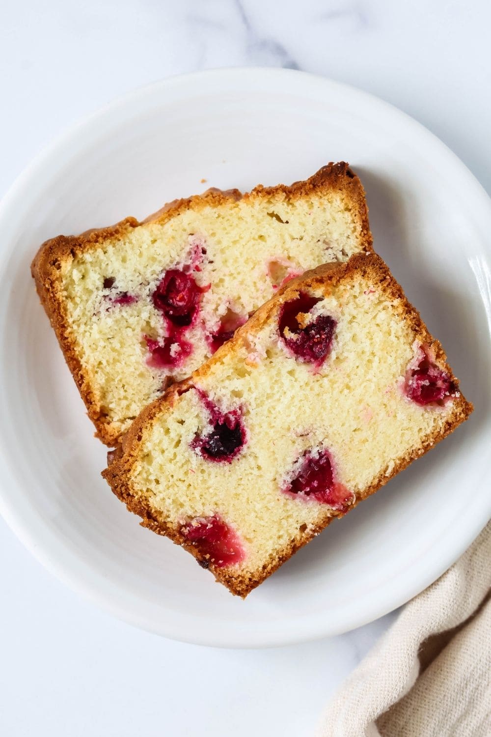 overhead view of two slices of moist cranberry quick bread, made from cake mix, served on a white plate.
