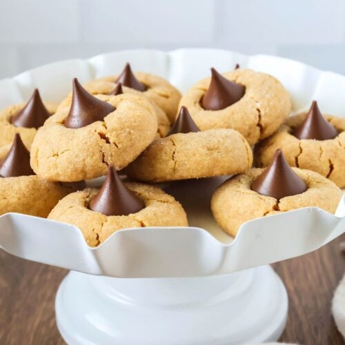 a white dessert stand displays several cake mix peanut butter blossom cookies.