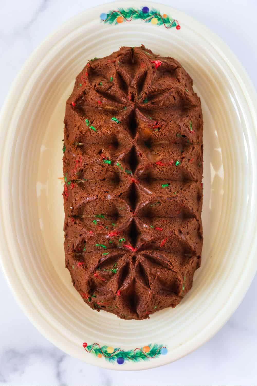 overhead view of a loaf of Christmas bread that was baked in a fluted loaf pan, showcasing the shapely details and red and green sprinkles.