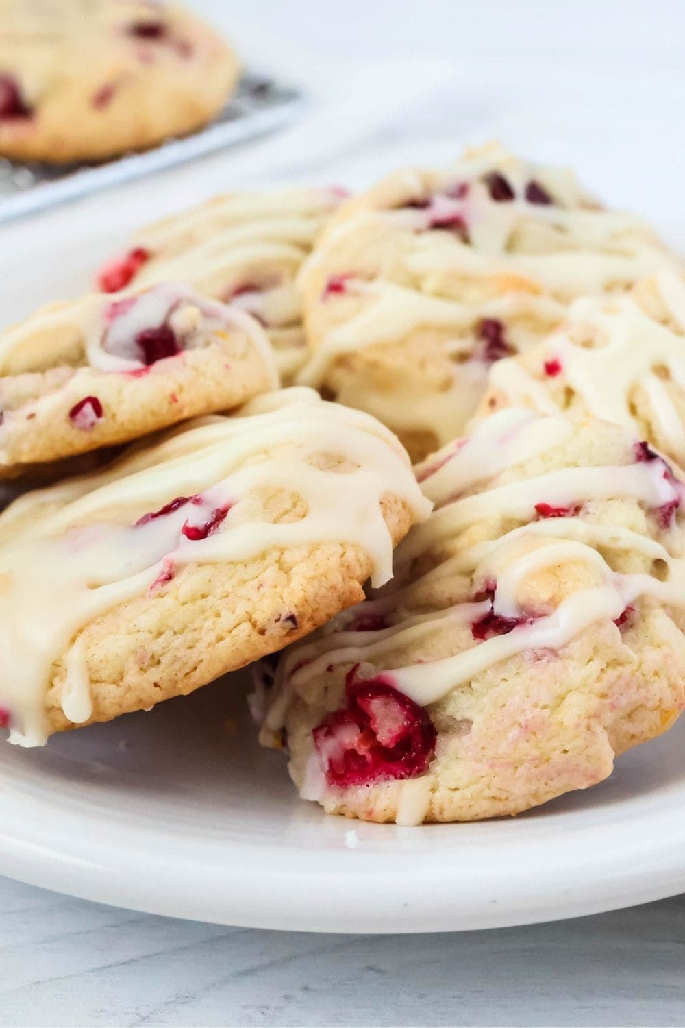 close-up view of a few iced cranberry orange cookies made with cake mix, served on a white plate.