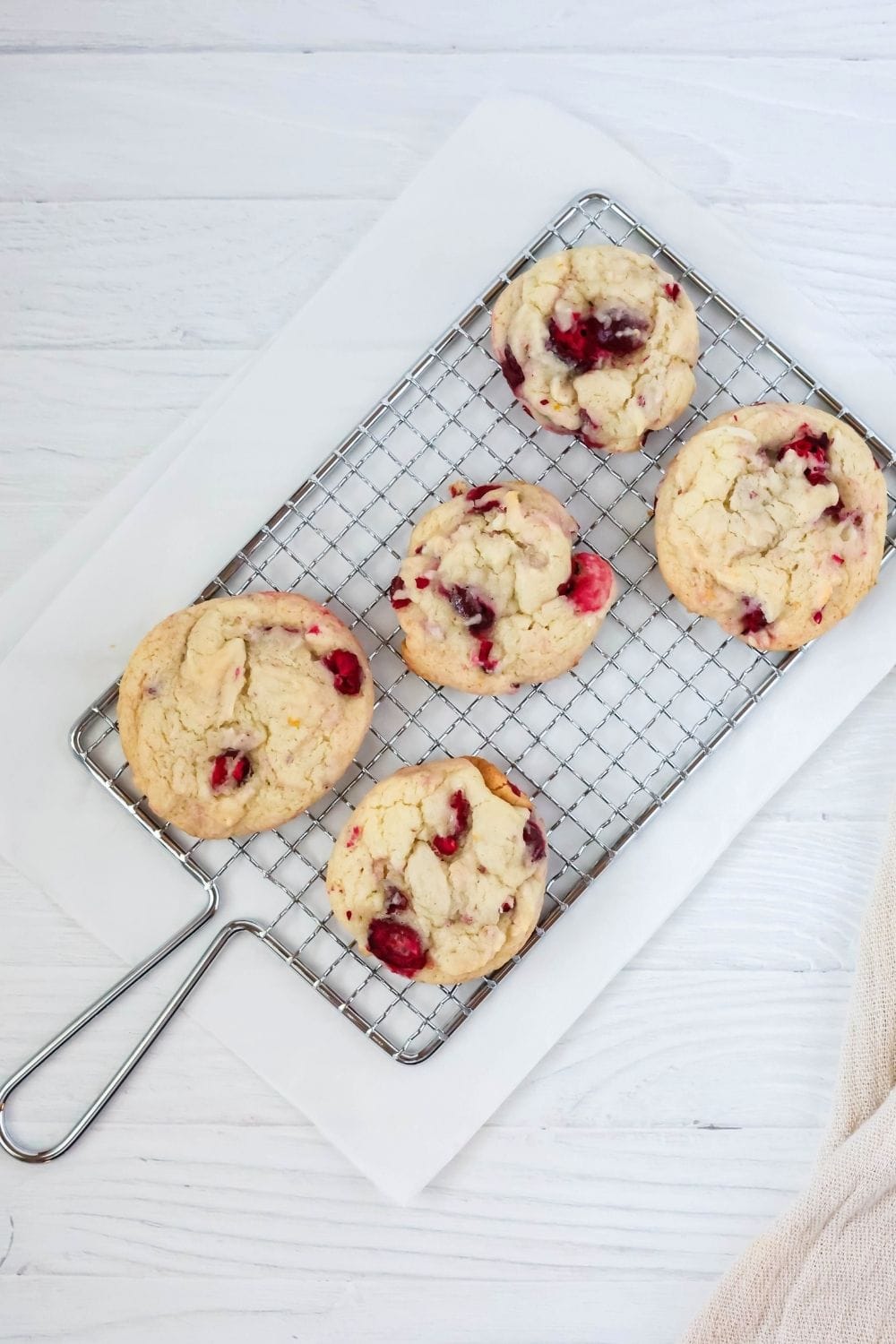 overhead view of fie cranberry orange cookies, without icing, on a wire rack.