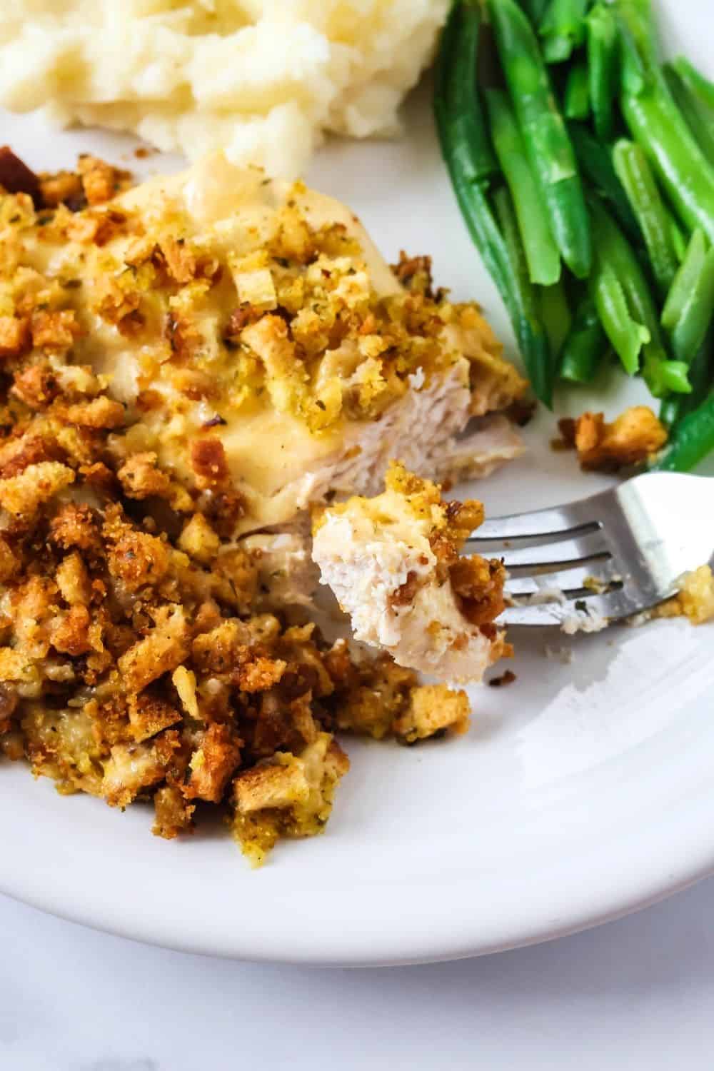close-up view of a fork with a bite of chicken and stuffing on it, resting on the plate of food.