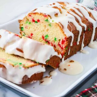 Funfetti Christmas bread loaf topped with icing and sliced, showing the red and green sprinkles in the bread.
