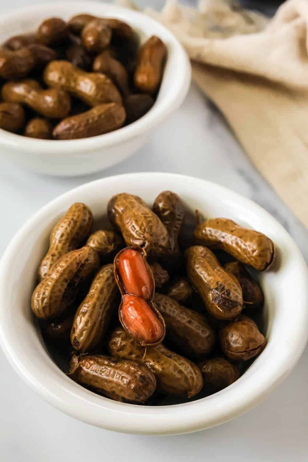 two white bowls filled with hot boiled peanuts from a slow cooker.