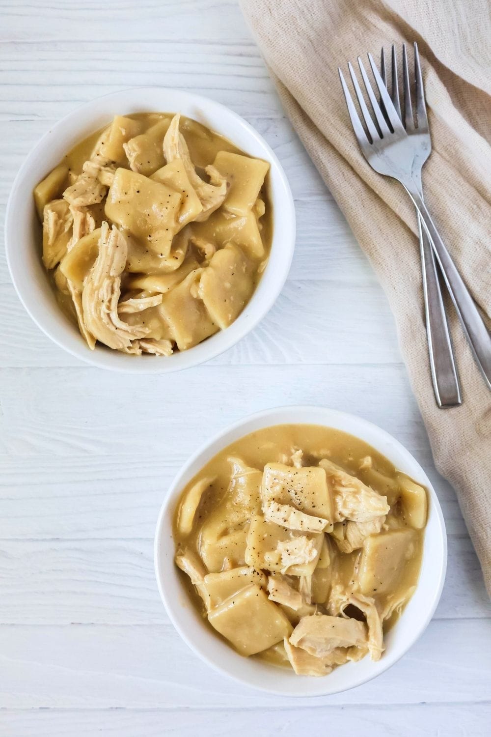 overhead view of two bowls of chicken and rolled dumplings made in the Instant Pot pressure cooker. Two forks are next to the bowls.