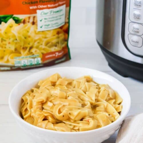 a bowl of Instant Pot Knorr pasta sides, with a package of Knorr sides and a pressure cooker in the background.