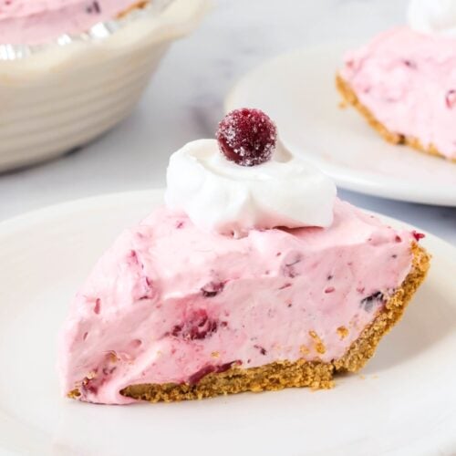 No-Bake Cranberry Pie slice served on a white plate, garnished with whipped cream and a whole cranberry.
