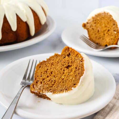 Two slices of pumpkin bundt cake from a mix, served on white plates, with the remainder of the whole bundt cake in the background.