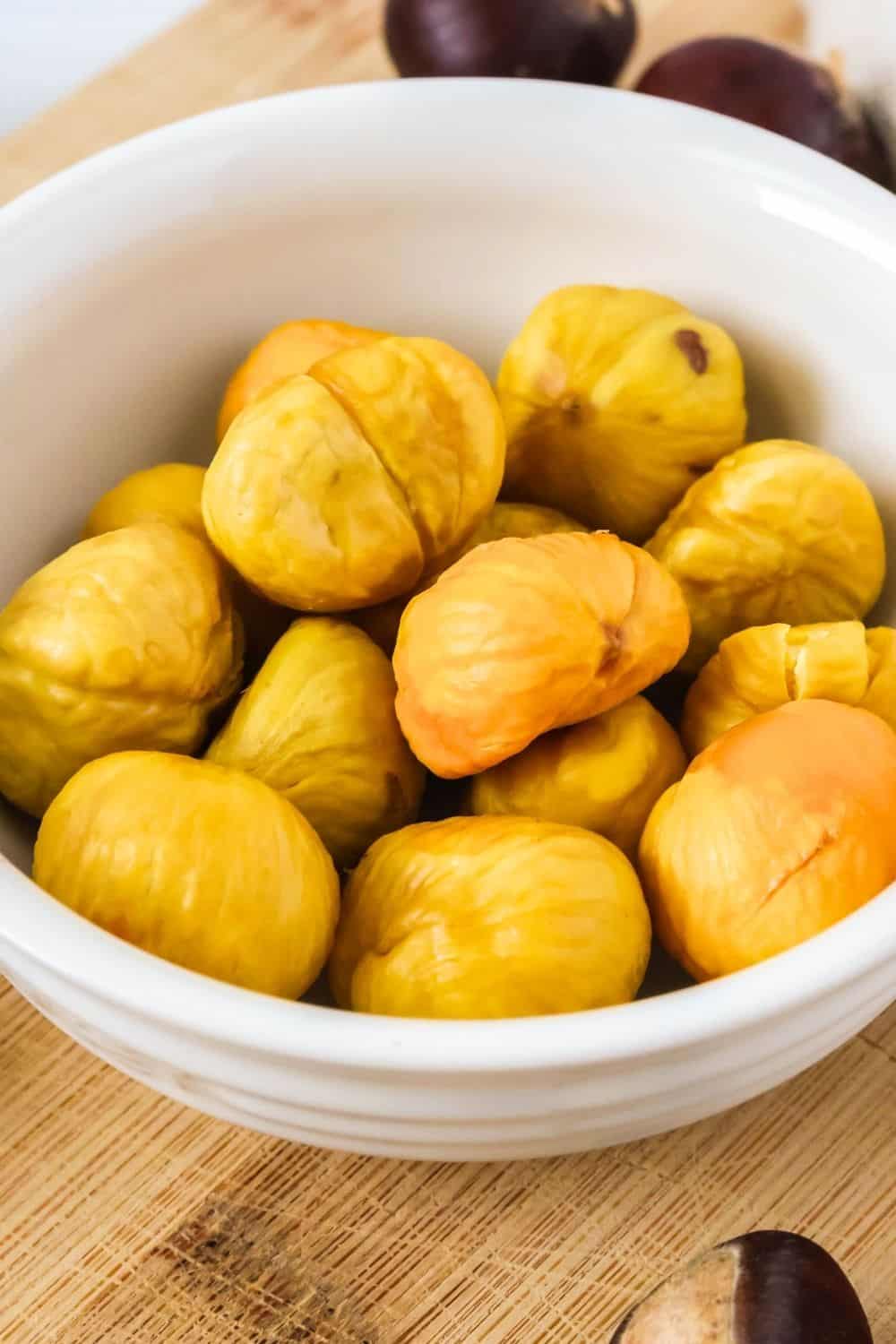 close-up view of a white bowl of oven-roasted chestnuts.