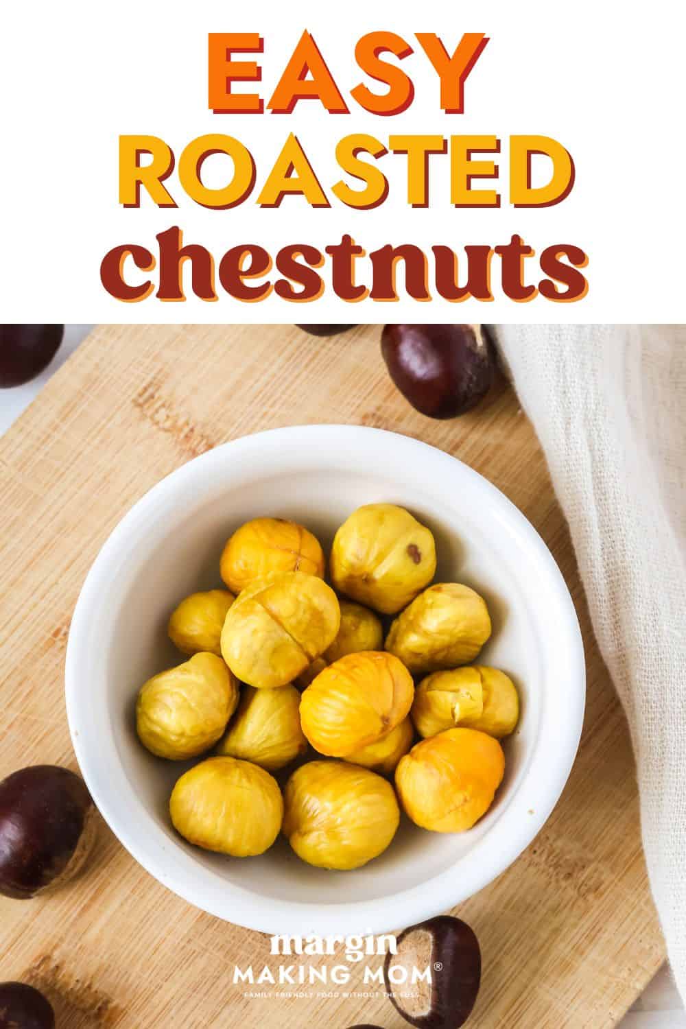 overhead view of a white bowl of roasted chestnuts with the peeling removed. Scattered around the bowl are more fresh chestnuts.