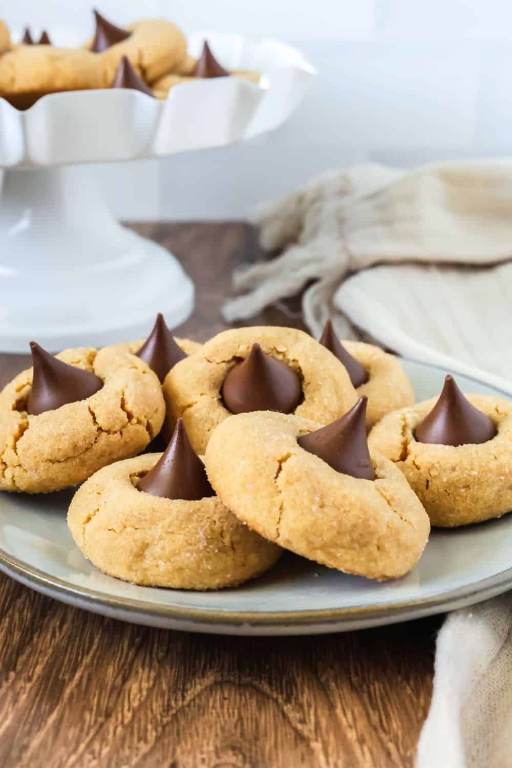 a plate full of Christmas peanut butter blossoms made from cake mix, with a dessert platter of more cookies in the background.