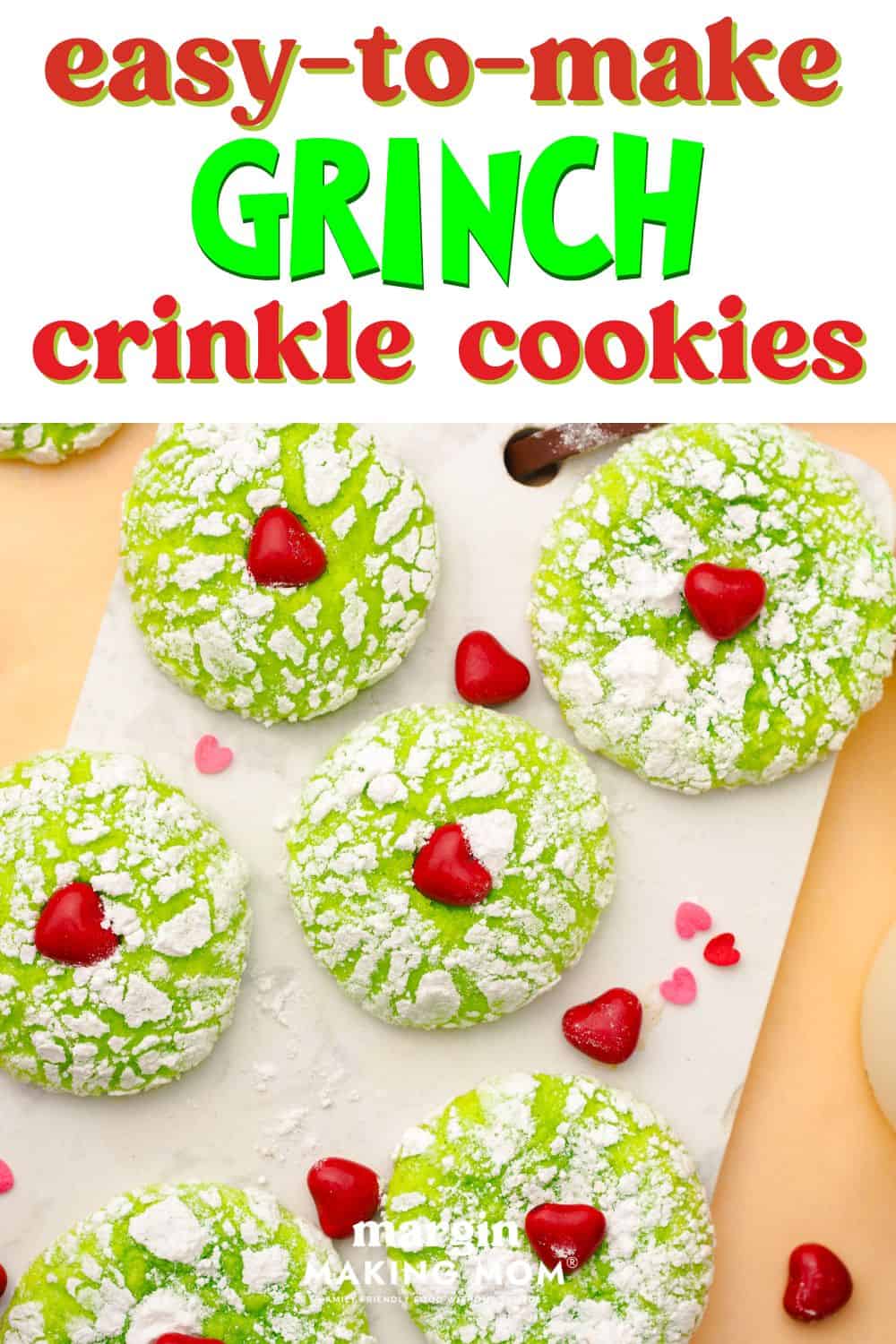 overhead view of several Grinch crinkle cookies on a piece of parchment paper, with red candy sprinkles around them.