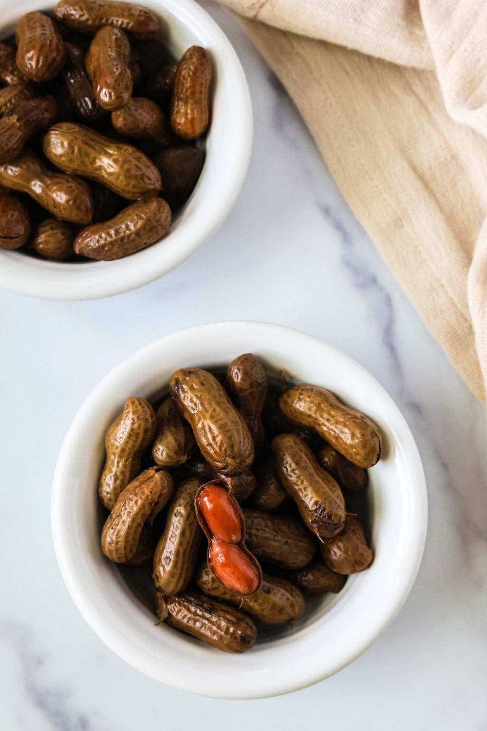 overhead view of two individual serving bowls of slow cooker boiled peanuts.