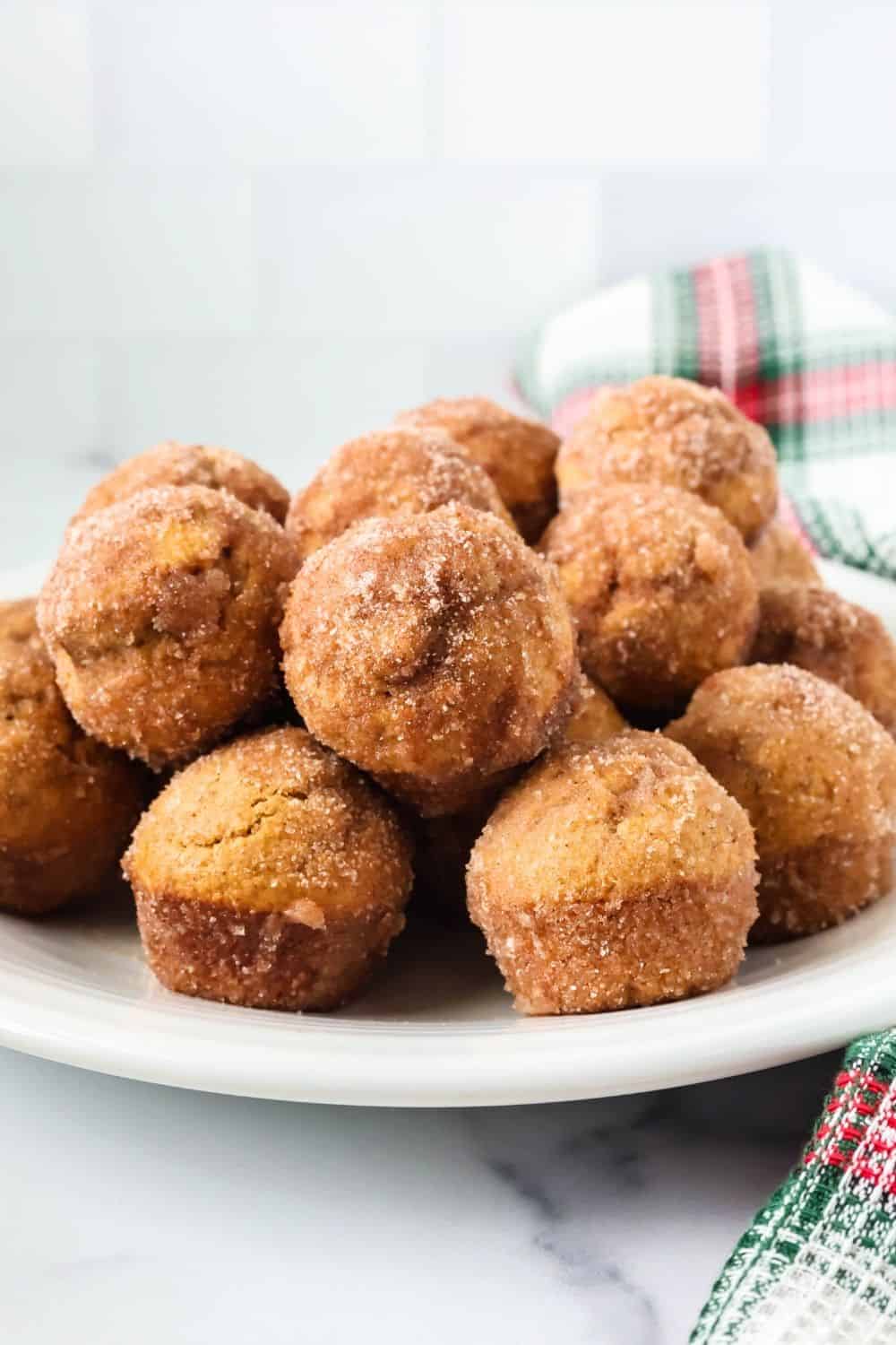 side view of a stack of gingerbread donut bite mini muffins for Christmas, served on a white plate.