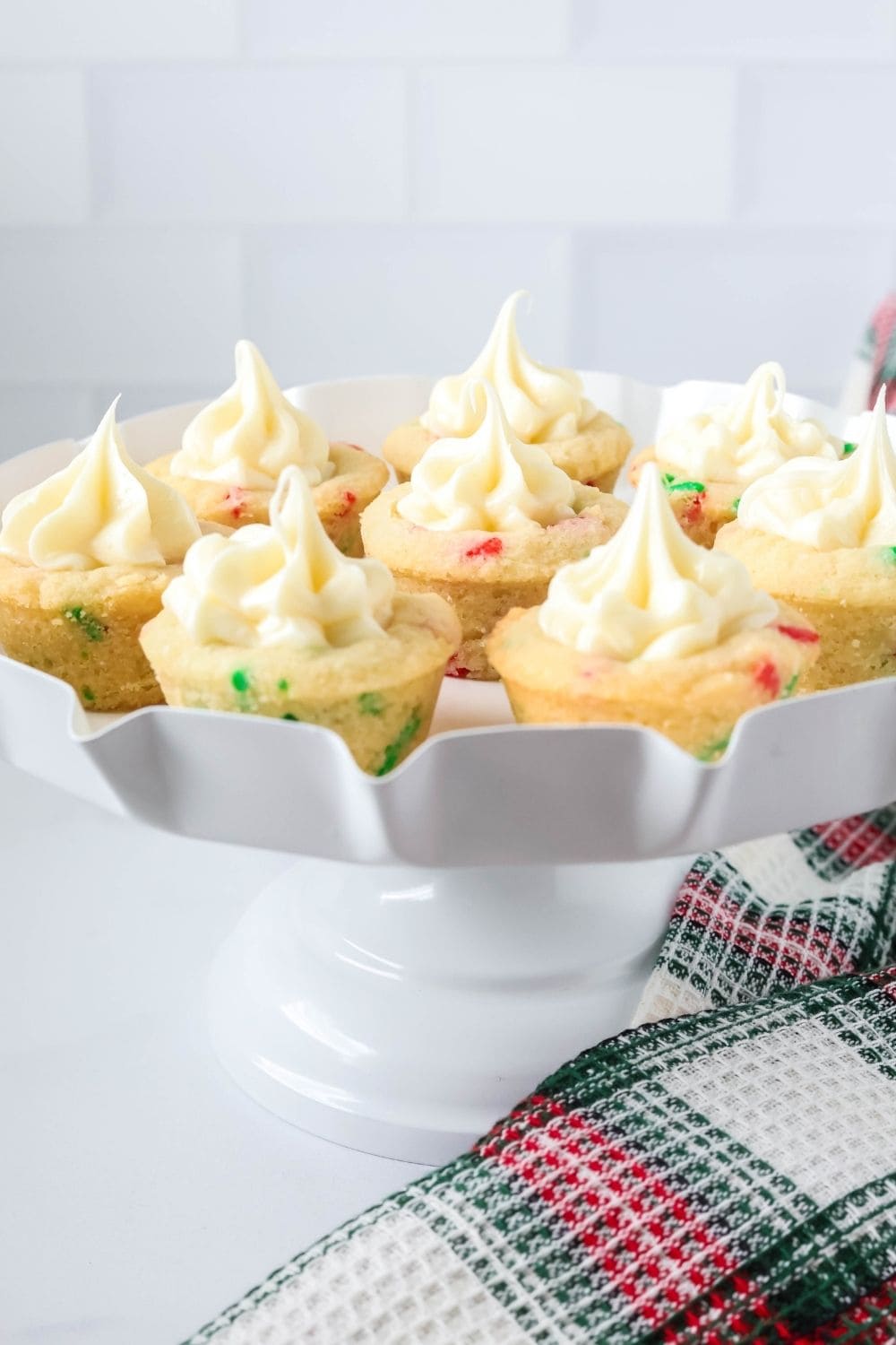 Confetti Christmas cookie cups with frosting served on a white dessert stand.