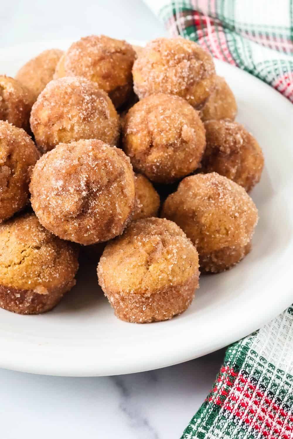 close-up view of several Christmas gingerbread donut bites made with Bisquick, coated in cinnamon sugar and served on a white plate.