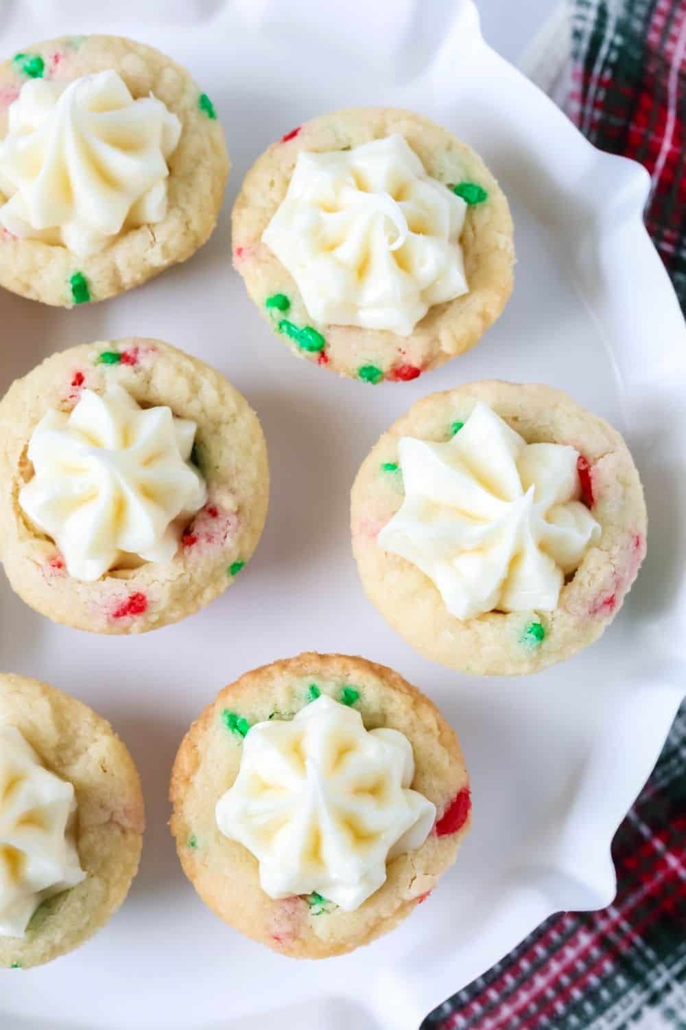 overhead view of red and green sprinkle sugar cookie cups filled with vanilla frosting.