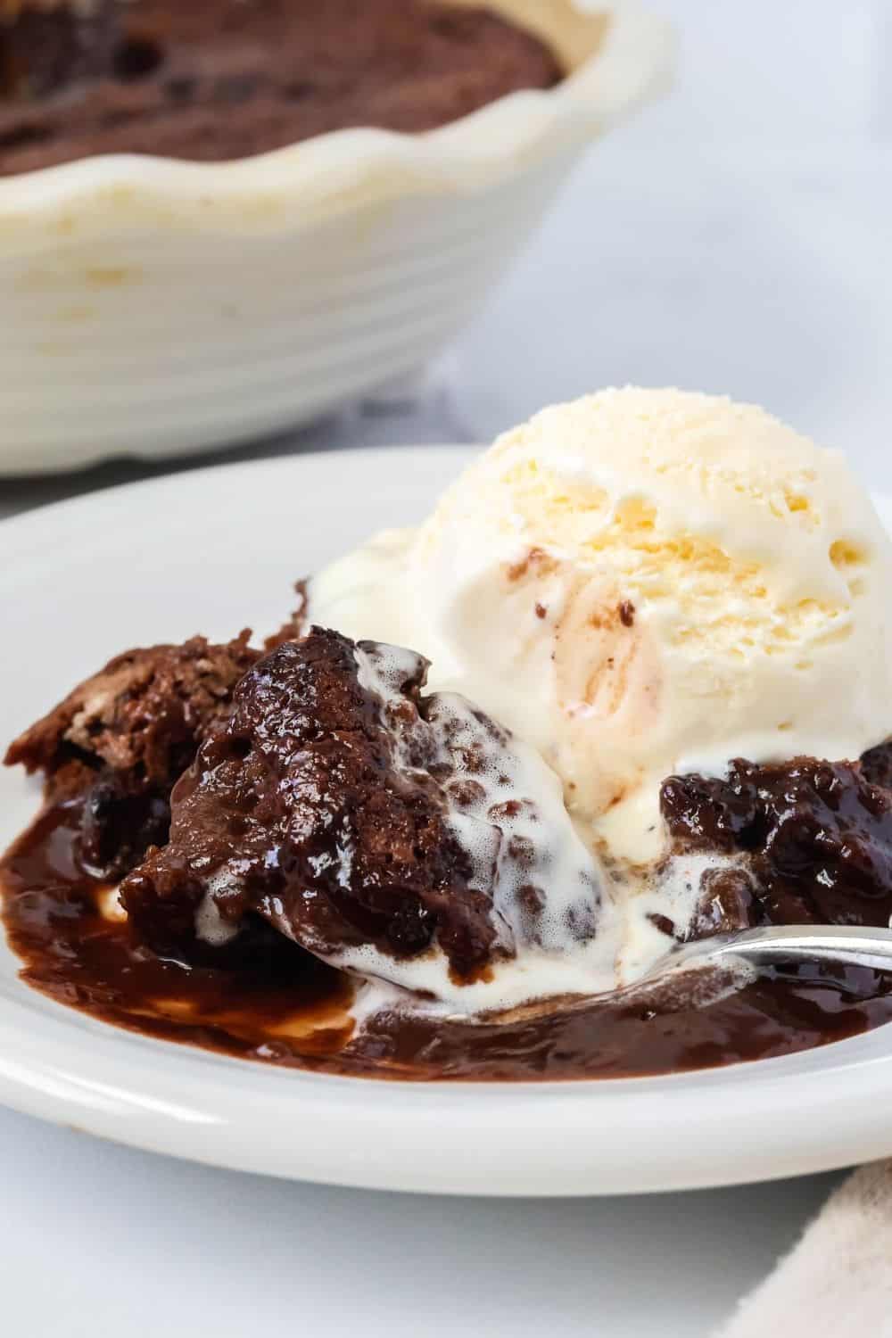 close-up view of chocolate cobbler made with Bisquick, topped with ice cream, and a spoon is scooping out a bite.