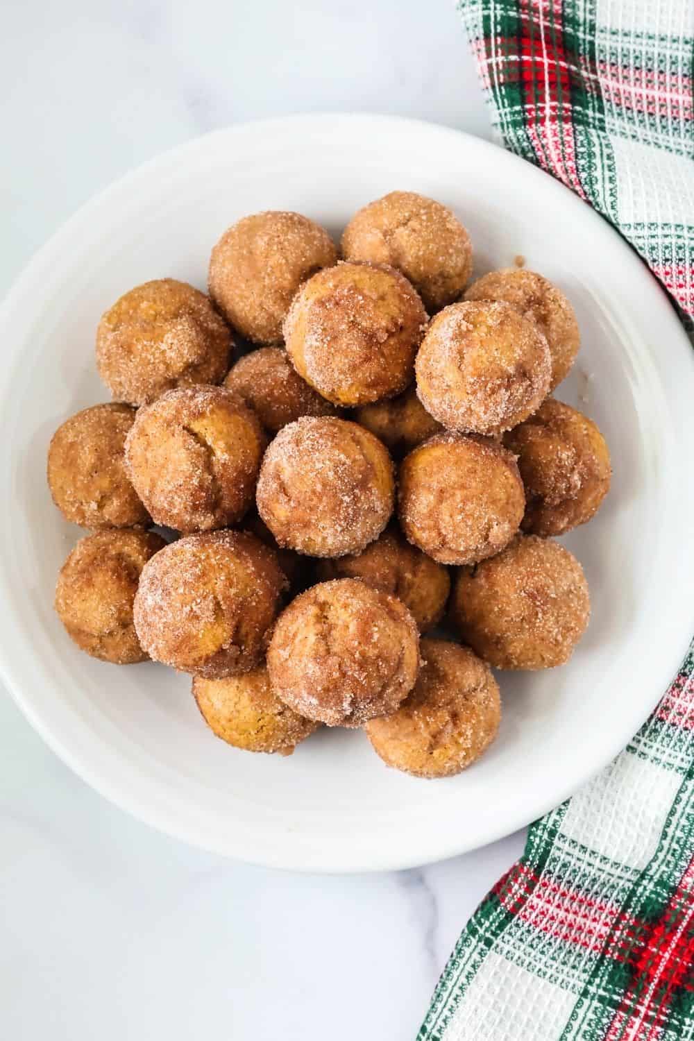 overhead view of a white plate with a pile of gingerbread donut mini-muffins on it.