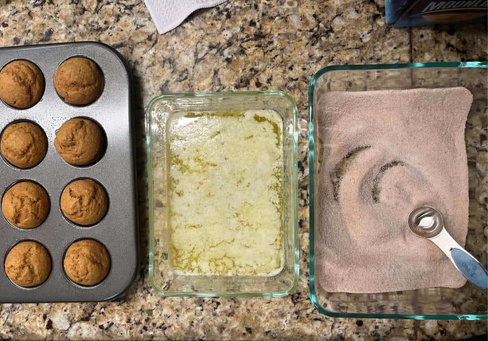 melted butter in a glass dish, cinnamon sugar in another glass dish, and gingerbread mini-muffins.