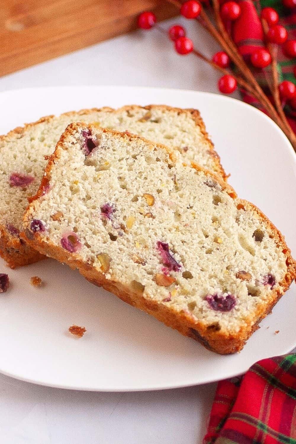 close-up view of two slices of scratch-made cranberry pistachio bread on a white plate.