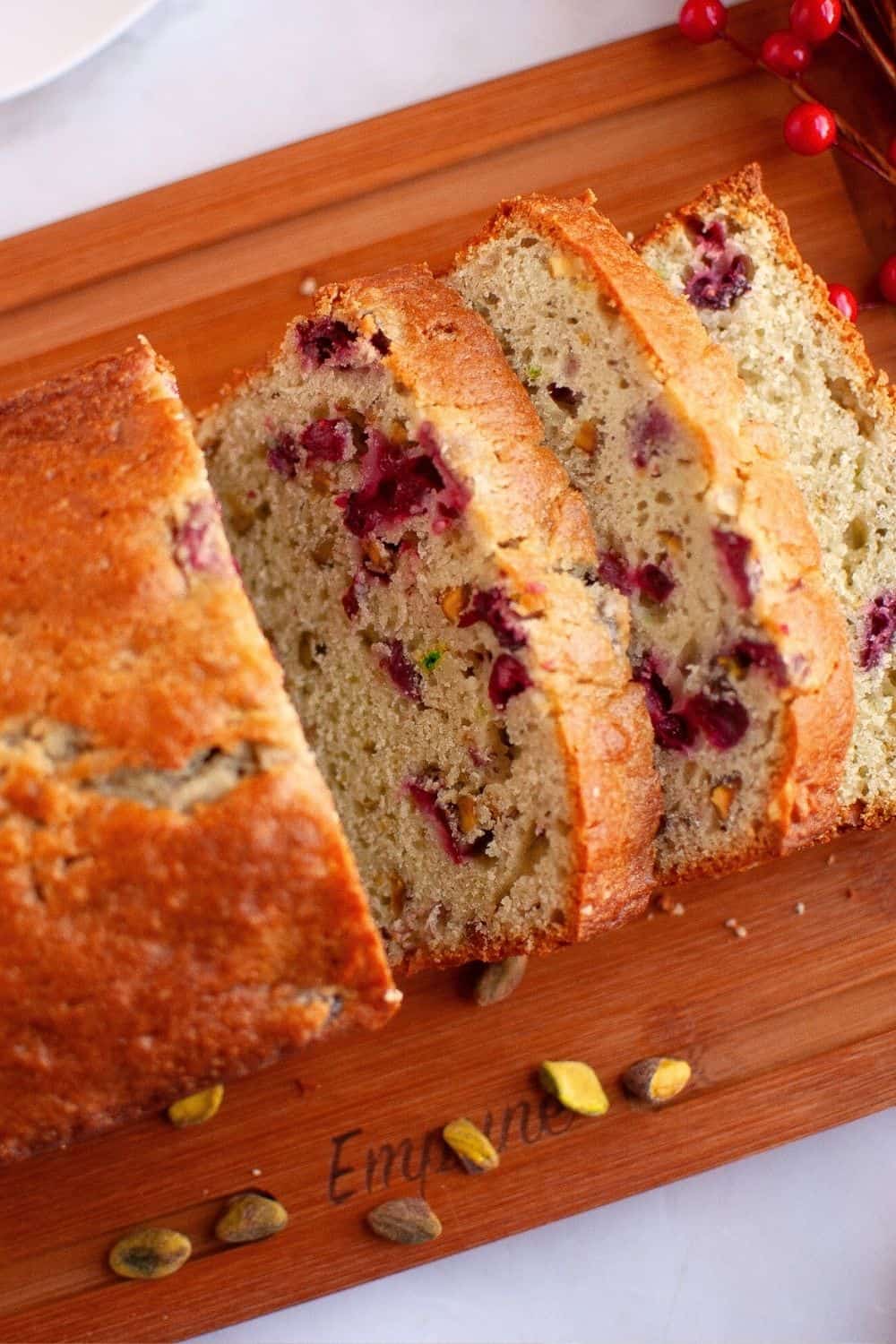 sliced loaf of pistachio cranberry bread made without cake mix, displayed on a cutting board.