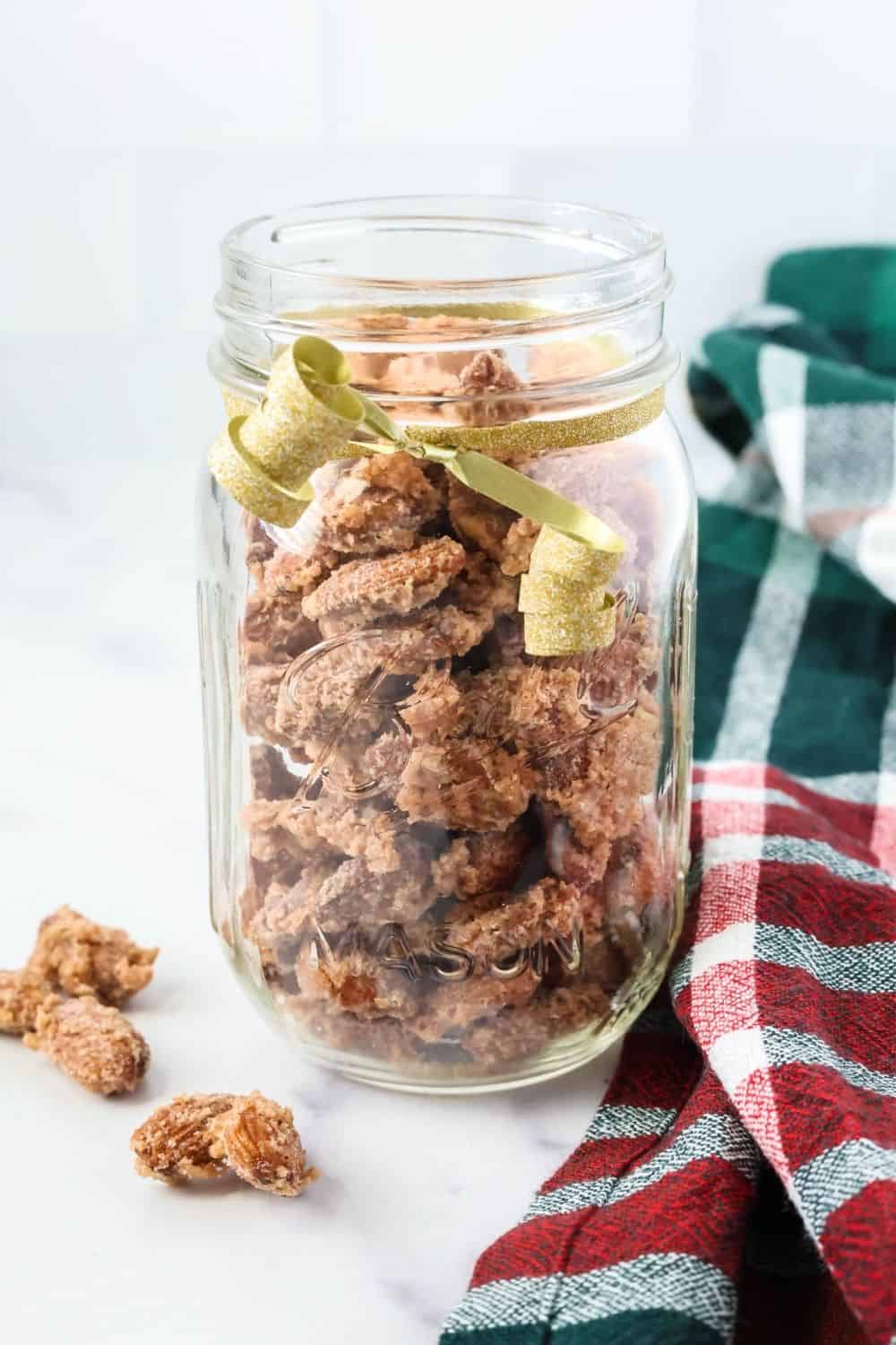 mason jar of cinnamon sugar almonds with a gold ribbon tied around the jar for gifting as a handmade gift.