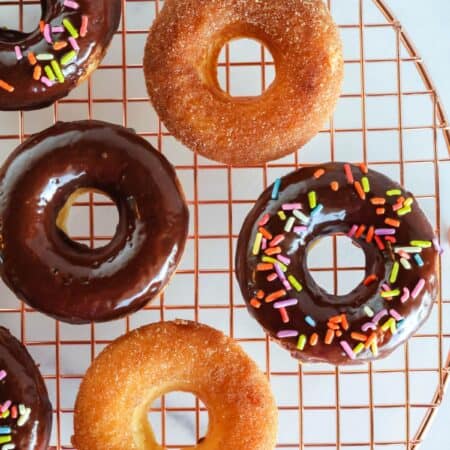 overhead view of Bisquick baked donuts on a wire rack. Some are topped with chocolate glaze and some are topped with cinnamon sugar.