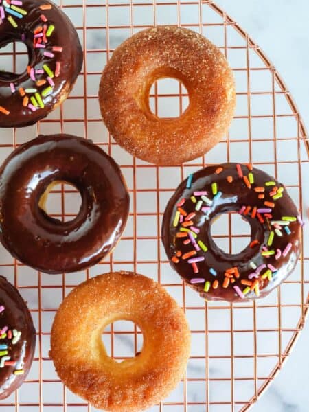 overhead view of Bisquick baked donuts on a wire rack. Some are topped with chocolate glaze and some are topped with cinnamon sugar.