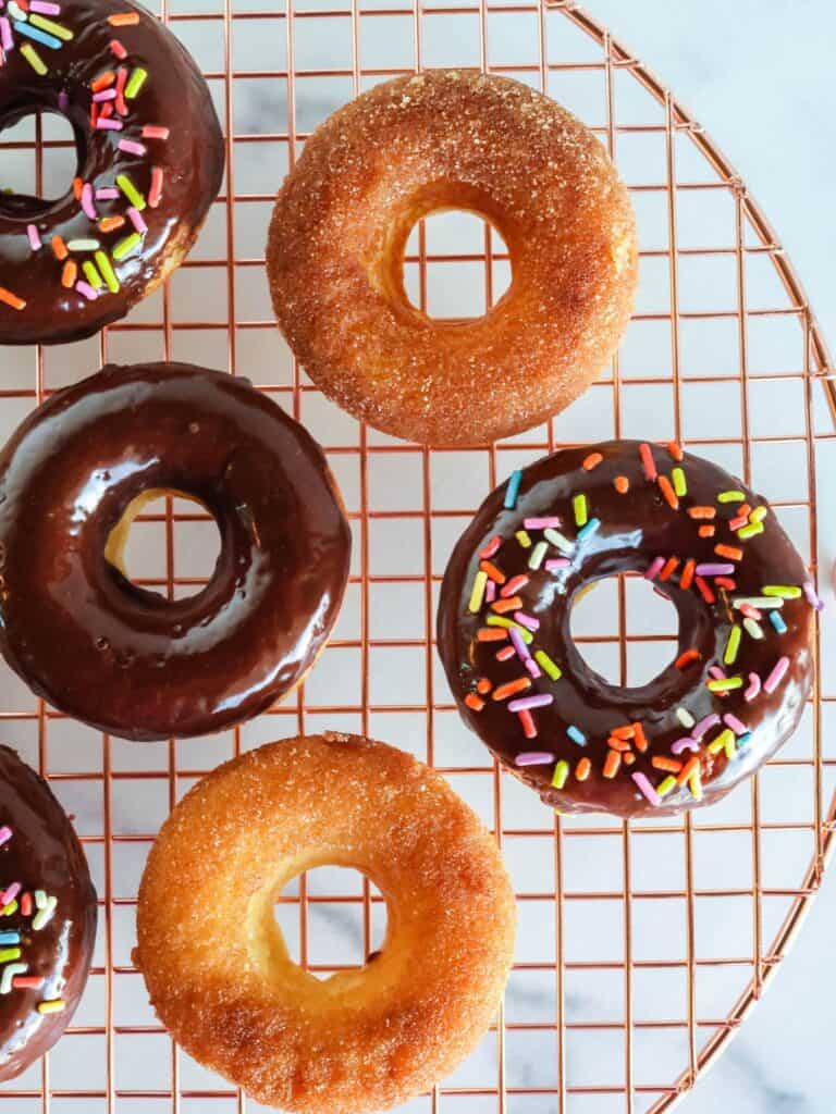 overhead view of Bisquick baked donuts on a wire rack. Some are topped with chocolate glaze and some are topped with cinnamon sugar.