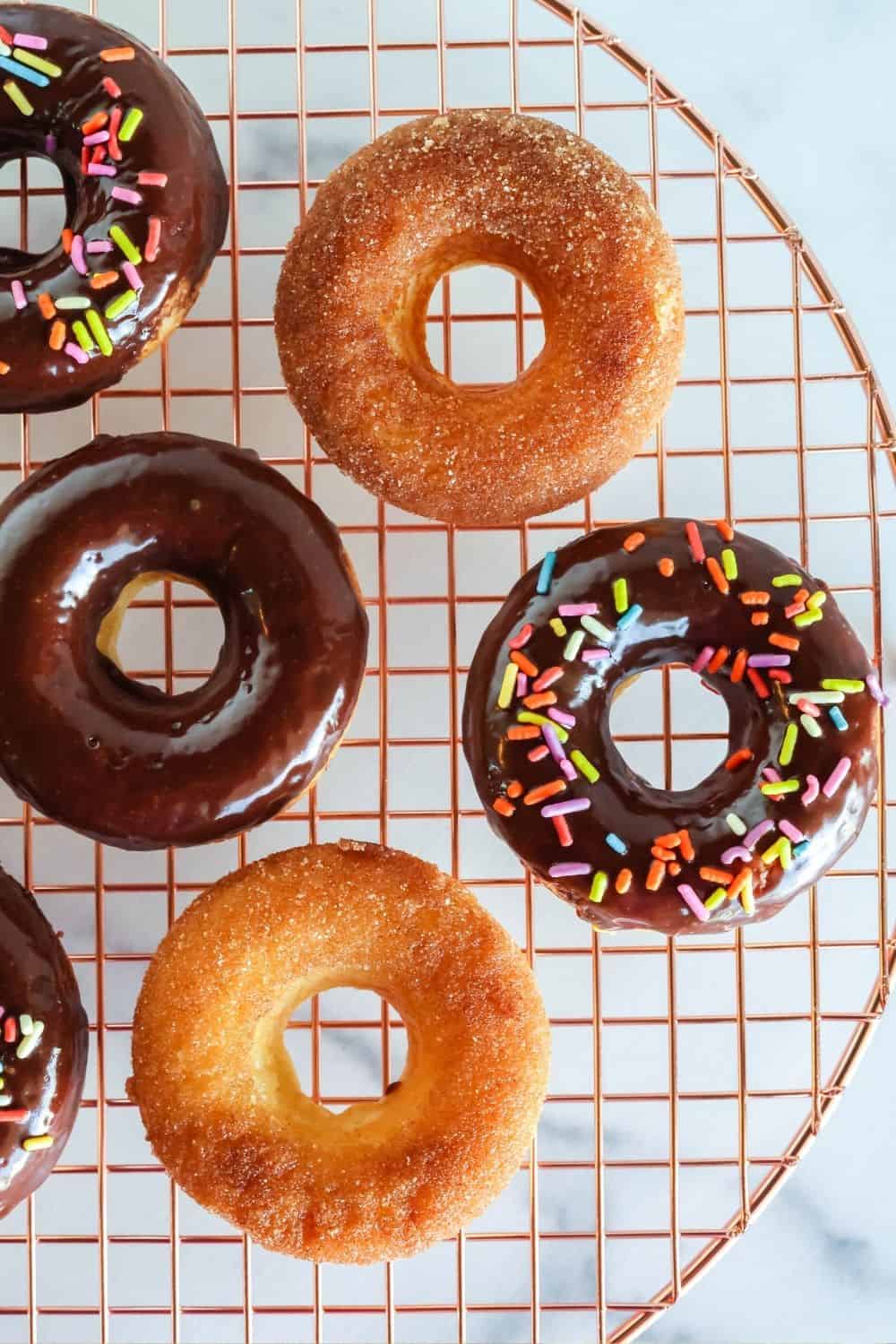 close-up overhead view of cake donuts made with Bisquick, served on a wire rack, with various toppings on the donuts.