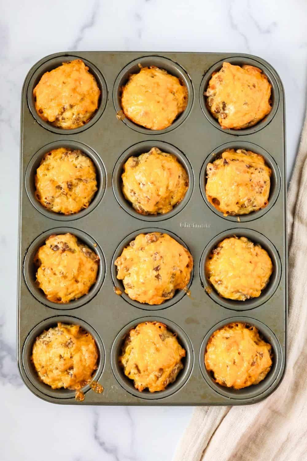 overhead view of muffin pan with freshly baked sausage egg and cheese muffins in it.