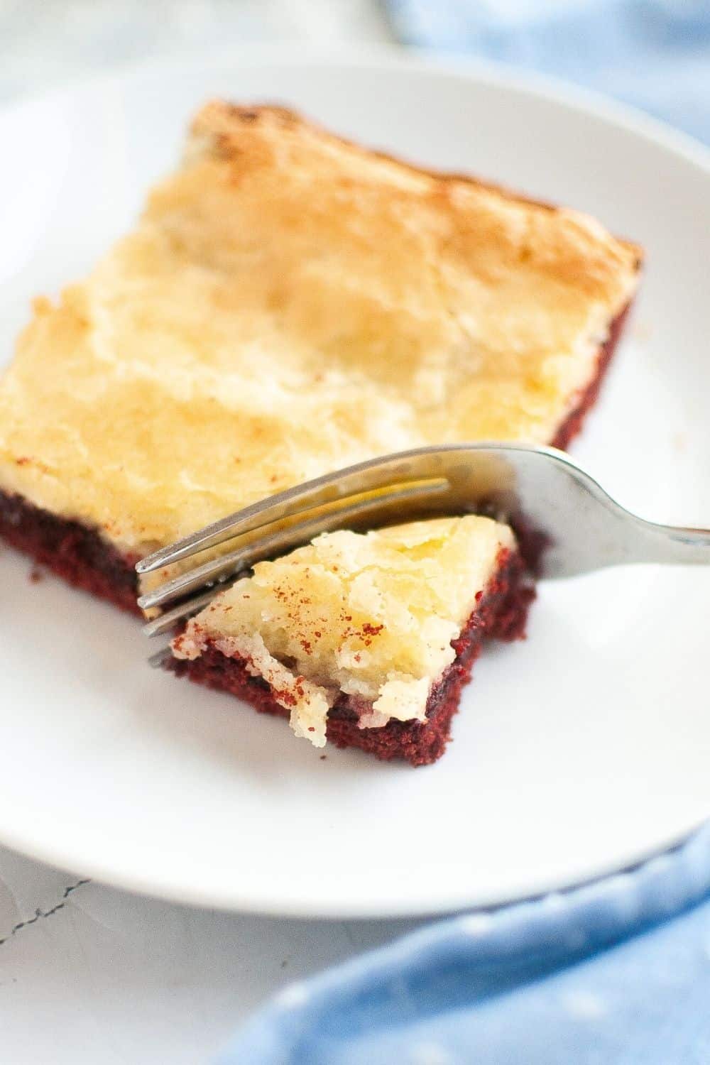 a fork slices into a square of holiday red velvet ooey gooey bars.