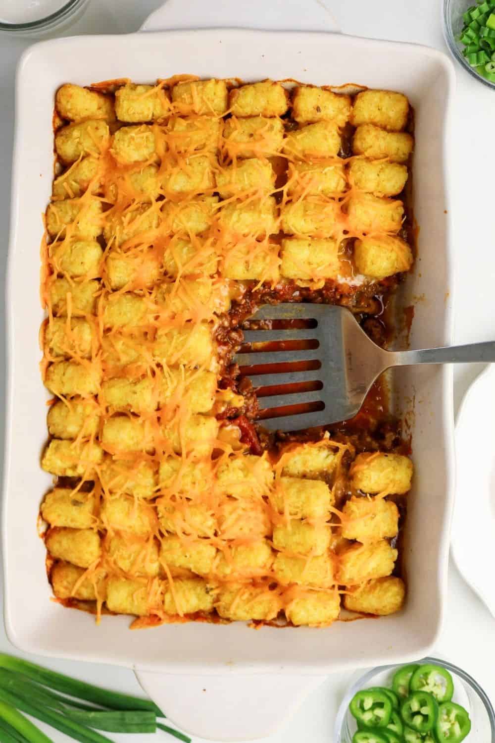 Spatula resting in the casserole dish of chili tater tot bake.