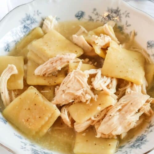 Crock Pot chicken and frozen dumplings served in a blue and white floral china bowl, showcasing the flat dumplings and chunks of tender chicken.