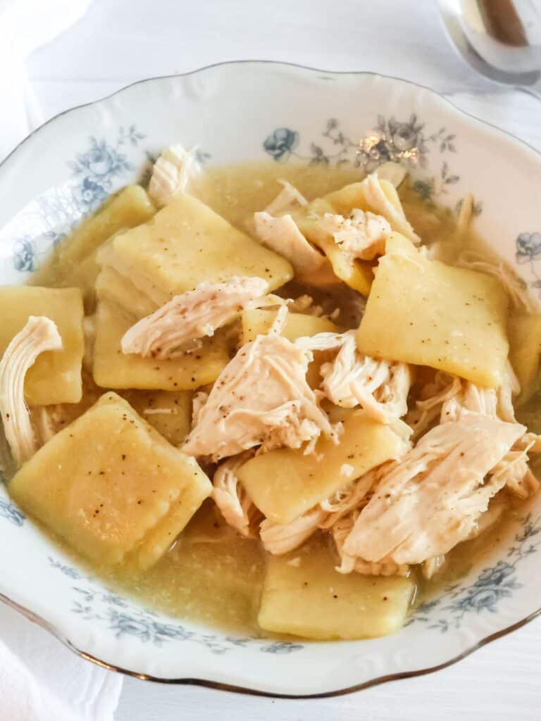 Crock Pot chicken and frozen dumplings served in a blue and white floral china bowl, showcasing the flat dumplings and chunks of tender chicken.